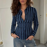Woman wearing a blue and black striped shirt with a deep neckline.
